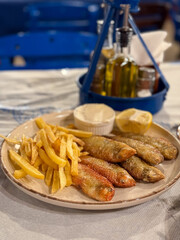 Traditional Greek Dish Fried Rouzetia Fish with French Freis and Lemon in Greek Tavern on Rhodes island