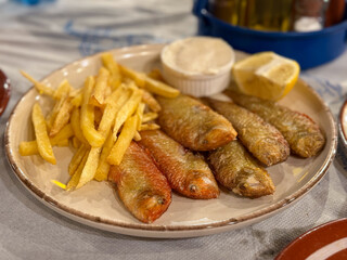 Traditional Greek Dish Fried Rouzetia Fish with French Freis and Lemon in Greek Tavern on Rhodes island