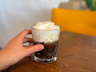 Freddo Cappuccino Greek iced coffee drink in with espresso and cold frothy milk in female hand...
