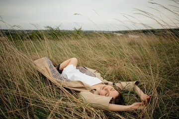 Young woman relaxing in tall grass enjoying nature's embrace