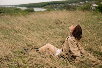 Model relaxing in tall grass during outdoor photoshoot with river view © Andrii