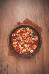 saganaki with shrimp, in a clay pan, Greek dish, shrimp in tomato sauce, feta cheese, homemade, no people,