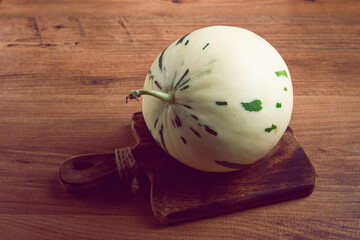 Dino melon, white with green stripes, small size, on the table, close-up, no people,