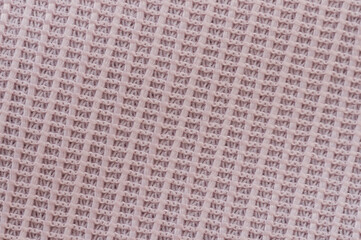 Close-up of textured fabric displaying fine woven pattern in soft pink color