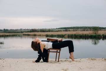 Young woman performing a photoshoot on a chair by the lake