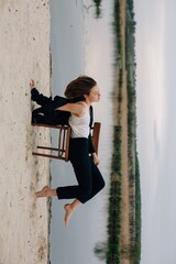 Young model posing on chair by the lake during photo session