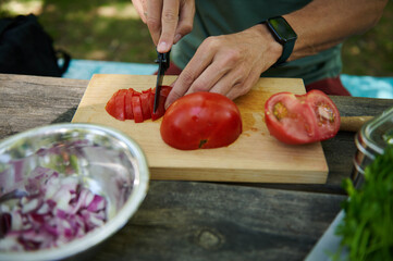 Close-Up of Hands Slicing Fresh Tomatoes on a Wooden Board Outdoors