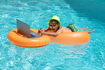 Summer business. Child sitting in swimming ring in pool and using laptop. Shopping online,...
