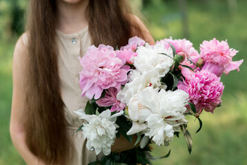 girl holding pink flowers peonies in the garden