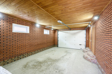 interior garage space featuring brick walls, a light wooden plank ceiling, concrete floor, a white...