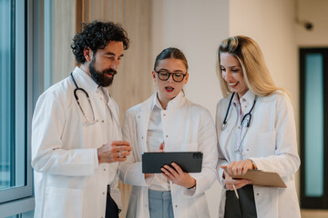 Doctors using tablet and discussing diagnosis in hospital corridor