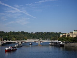 Obraz premium A picturesque river scene with bridges, boats, and a lush green bank.