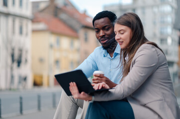 Businesspeople working with laptop and drinking coffee outdoors in the city