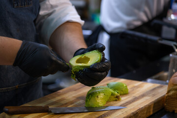 Cook chops fresh avocados for tasty appetizers in a lively kitchen