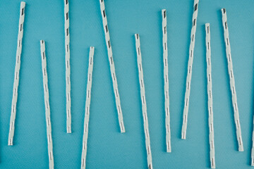 Silver striped paper straws on blue background for holiday drinks or modern party themes