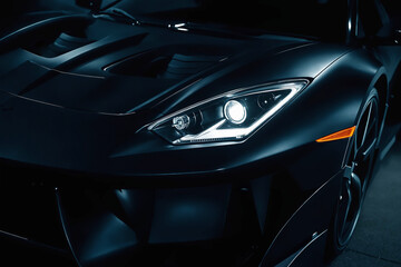 A black car with headlights on in a dark studio