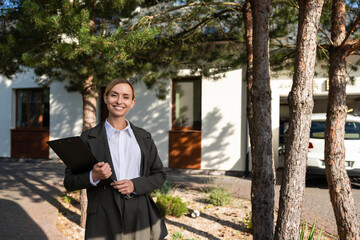 Smiling female real estate agent holding a key from the house