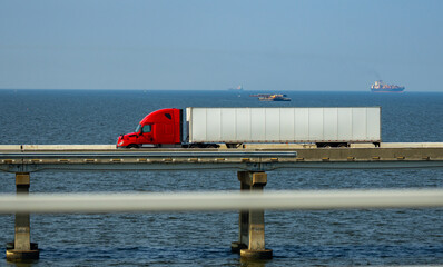 Truck driving across the bridge near sea or ocean. Lorry transporting. Cargo trailer. Logistics...