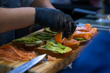 Preparing gourmet salmon avocado toast in a professional kitchen setting
