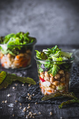 Layered salad in a glass: raw vegetables, chickpeas and green leaf lettuce