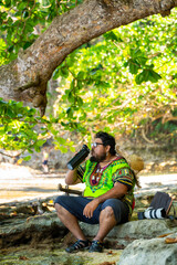 Local Costa Rican man in a Caribbean shirt drinking water by the Caribbean Sea on a beach in...