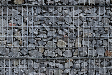 Rubble stone in galvanized mesh. Background. Gabion mattress made of woven mesh with stones for...