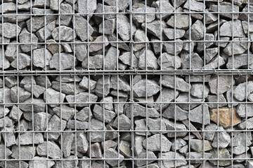 Rubble stone in galvanized mesh. Background. Gabion mattress made of woven mesh with stones for creating walls. Stones in mesh, creating decorative walls, strengthening