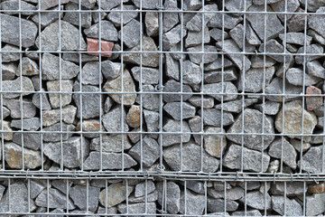 Rubble stone in galvanized mesh. Background. Gabion mattress made of woven mesh with stones for creating walls. Stones in mesh, creating decorative walls, strengthening