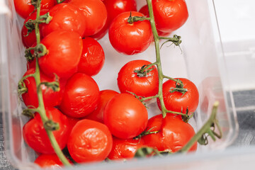 Fresh cherry tomatoes in box. Juicy red vegetables on vine. Healthy organic food in plastic...