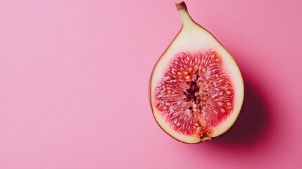 Photograph of a halved fig against a solid pink background, showcasing its intricate seed structure.