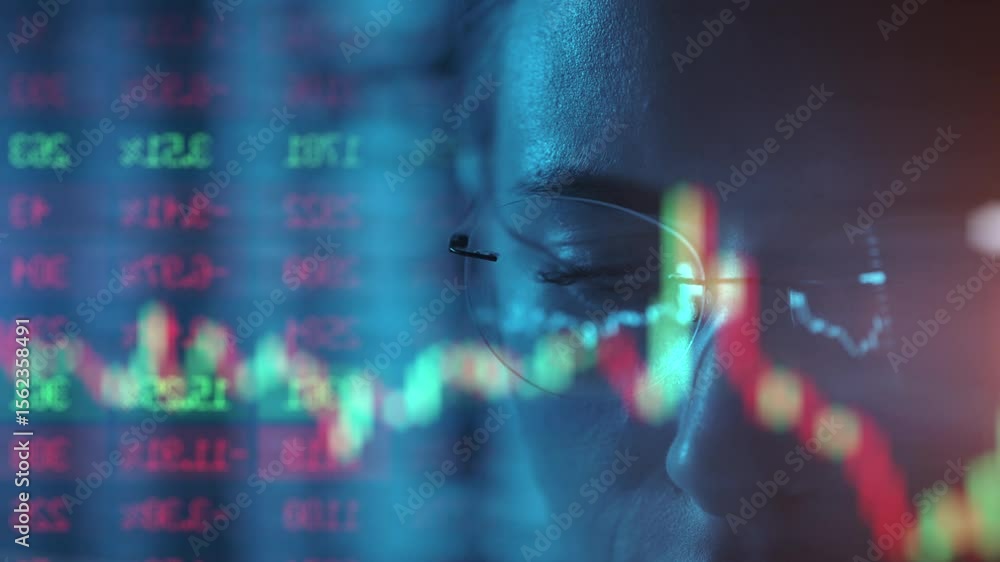 Poster trader wearing glasses is working on laptop computer. screen with stock market charts and bitcoin bt