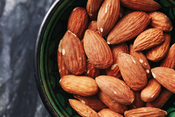 Whole almonds in bowl. Healthy natural snack. Nutritious food for diet. Organic protein source. Rustic kitchen concept. Dried nuts close up. Tasty vegan ingredient. Delicious crunchy superfood.
