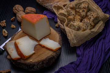 Rustic still life of semi-cured cheese slices with walnuts and multigrain bread in a basket on a...