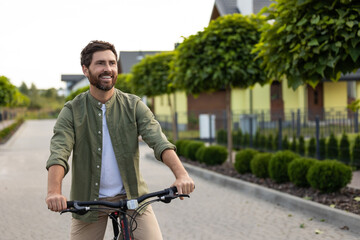 Naklejka premium Male cyclist riding on neighborhood trail with green scenery