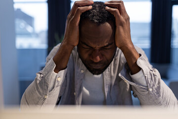 African american man at the laptop looking tired and suffering from a headache