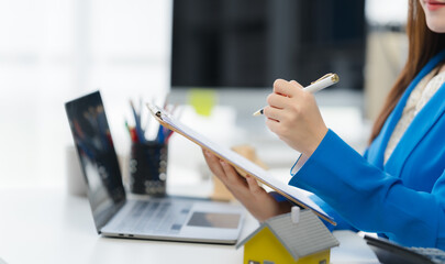 Property Professional at Work: A real estate professional meticulously reviews documents at her...