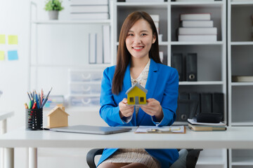 Real Estate Dream Weaver: An astute agent exudes confidence, presenting a miniature home that...