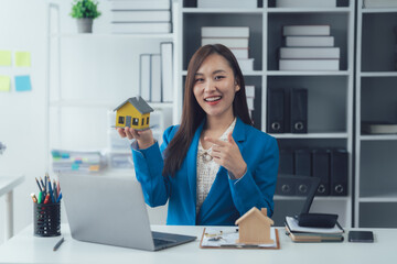 Real estate agent: Confident professional presenting a miniature house in an office environment,...