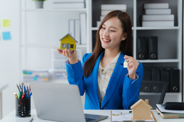 Real Estate Agent: A professional real estate agent in a modern office setting presents a miniature...