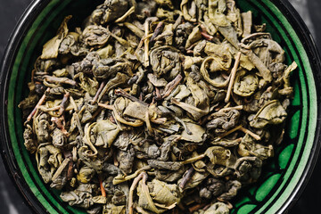 Dried green tea leaves in bowl. Organic herbal infusion ingredient. Natural Asian drink. Healthy...