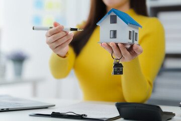 Real Estate Agent Showing House Model: A real estate agent presents a charming house model, keys,...