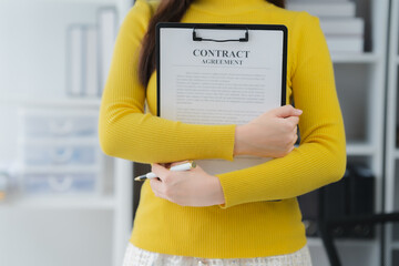 Contract Agreement and Professionalism: A focused individual dressed in a professional yellow top,...