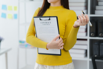 Businesswoman with Contract: An elegant professional, ready and prepared, stands with a contract,...