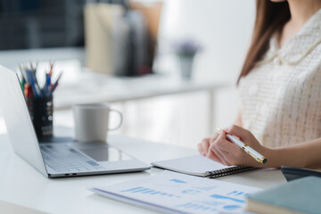 Focused Professional Woman: A close-up shot of a woman's hands meticulously writing notes in a...