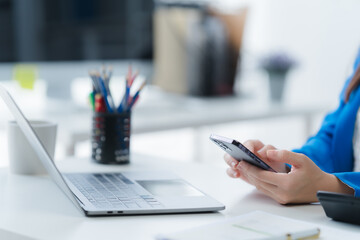 Modern Workspace: A focused professional in a light-filled office, engaging with their mobile phone...