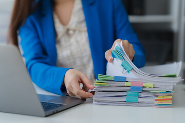 Workplace Efficiency: An elegant professional woman adeptly manages a comprehensive collection of files and papers, streamlining workflow with meticulous organization in a bright office setting.