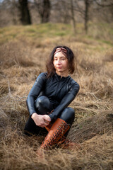 Girl in a field wearing a leather jumpsuit. Catsuit