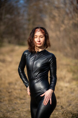 Girl in a field wearing a leather jumpsuit. Catsuit