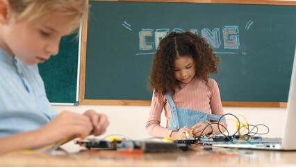 Girl standing while fixing electronic board by using screwdriver. American student and happy...
