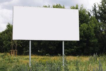Blank outdoor billboard in nature. Empty advertising banner on metal poles. Mockup template for...